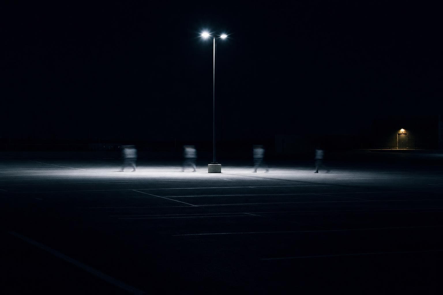 A single anonymous walking figure crosses the lamplit pool as only a handful of widely spaced, smeared motion-blur ghosts, each stride-position separated by black gaps where the body simply is not, so the walk dissolves and the movement falls into the dark spaces between the frozen postures.